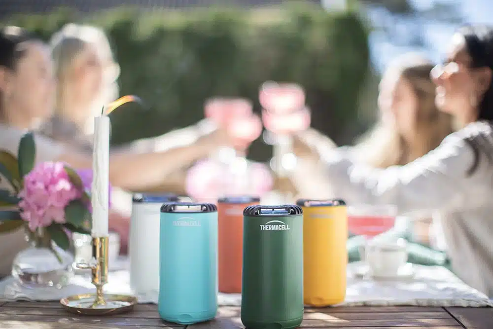 Utomhusmiddag med Thermacell-myggaavvisare och glada vänner som skålar i sommarsolen.
