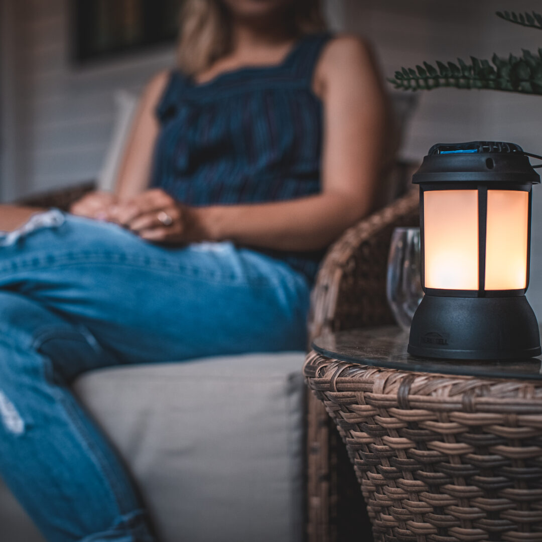 Kvinna sitter avslappnat med en lampa på ett sidobord i en mysig miljö.