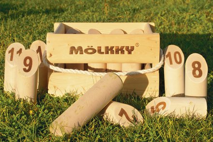 Mölkky spelset på gräsmatta, numerade käglor i trä.