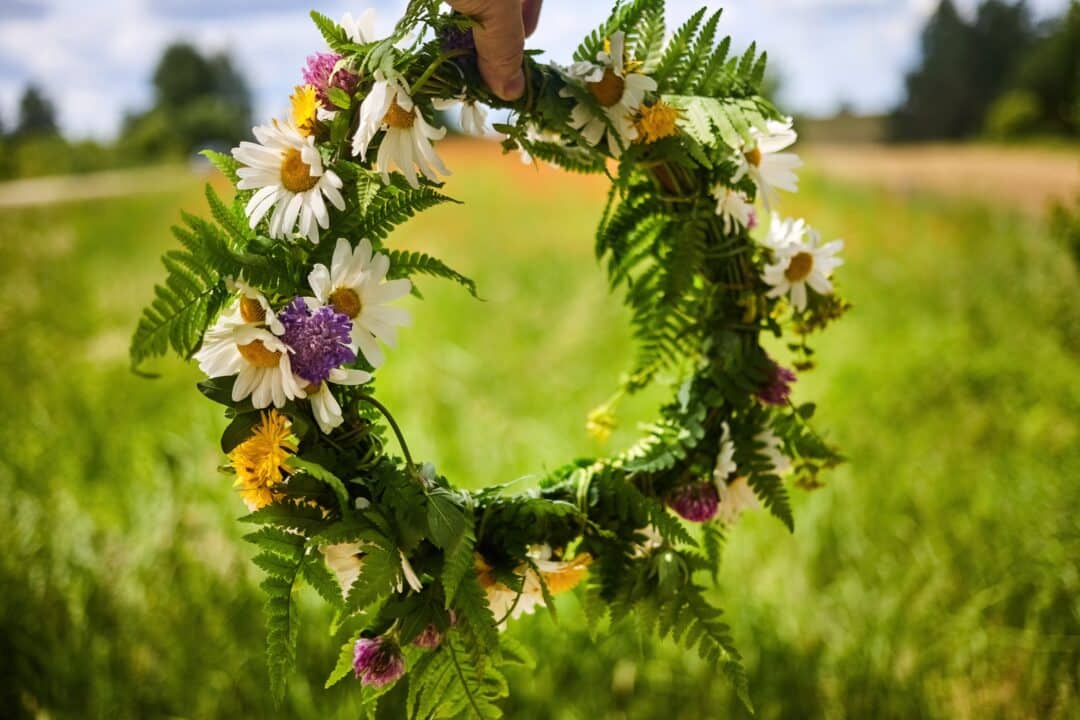 Blomsterkrans av sommarblommor i grönskande landskap.