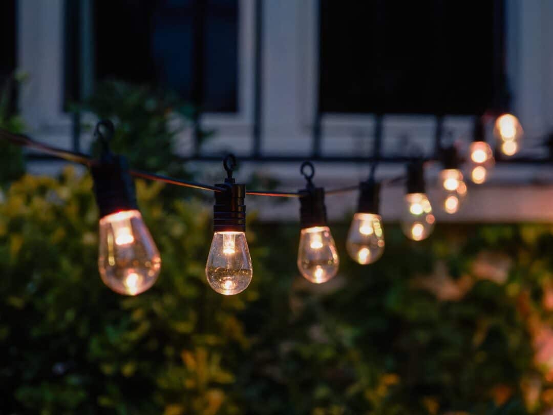 Ljusslinga med glödlampor i trädgårdsmiljö under kvällstid.
