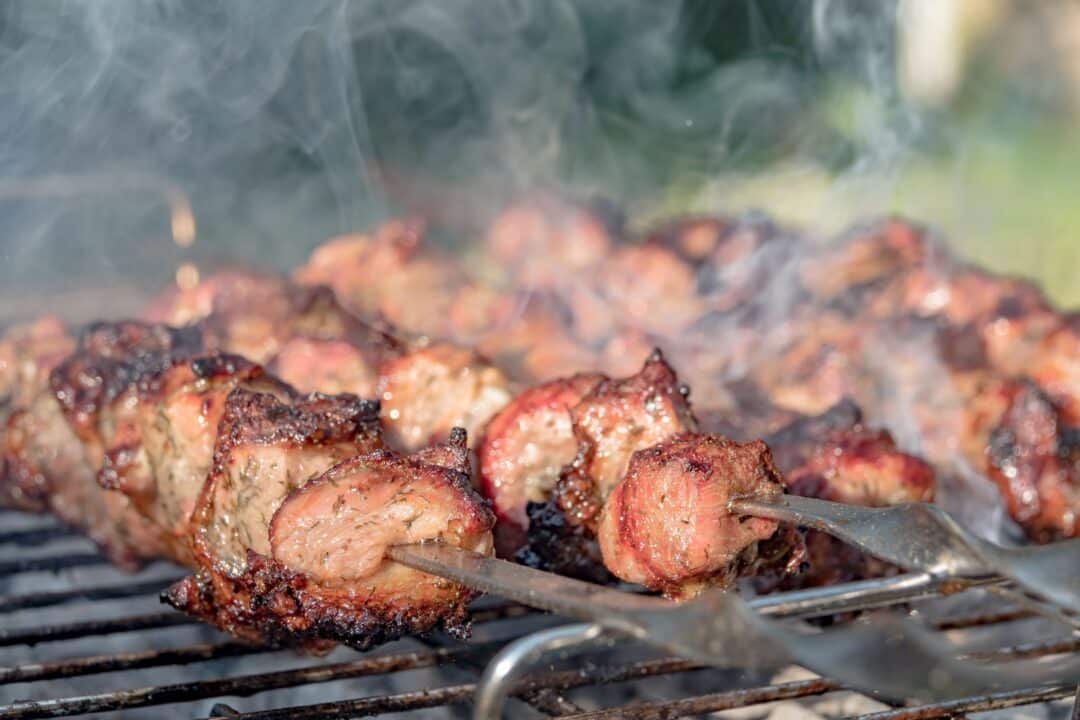 Grillat kött på spett med rök på barbecue-grill utomhus.