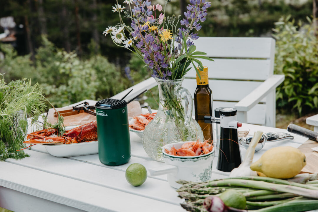 Ljust utebord med färsk skaldjur, blommor och ingredienser för en festmåltid.