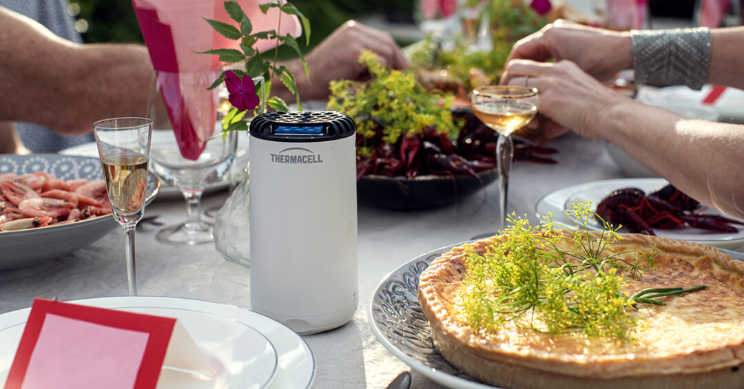 Alt-text: Ute på en sommarfest med en Thermacell myggavvisare vid maten och drycken.