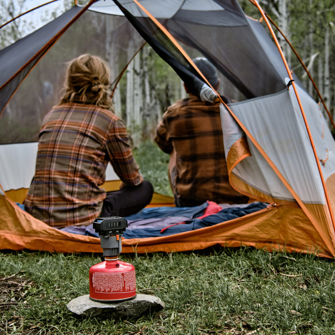 Två personer i en campingtält med en gasolbrännare i förgrunden.